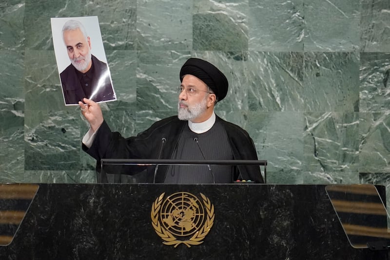 Mr Raisi holds up a photo of killed Iranian general Qassem Soleimani, as he addresses the 77th session of the United Nations General Assembly in 2022 (Mary Altaffer, AP)