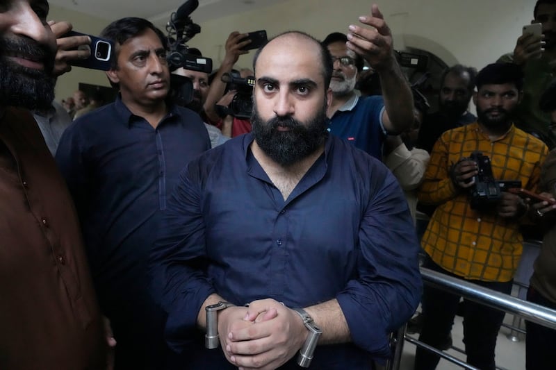 Plainclothes police officers escort Farhan Asif, centre, after his court appearance, in Lahore, Pakistan (AP Photo/K.M. Chaudary)