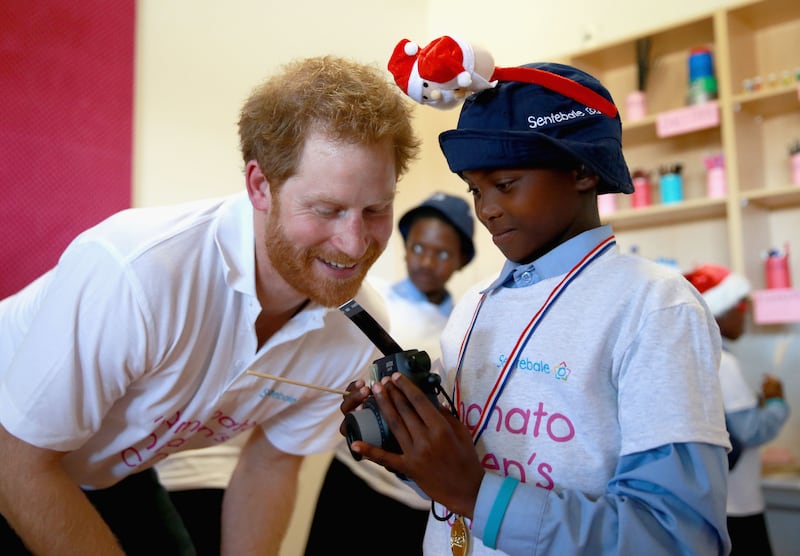 Harry helps a boy during a photography activity in Maseru