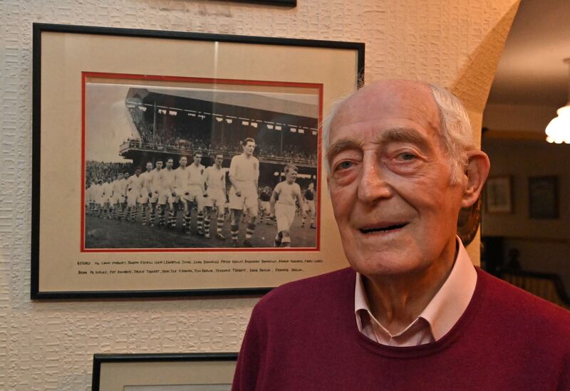 Jody O'Neill beside the framed photograph of him leading Tyrone out in the 1956 All-Ireland SFC semi-final against Galway.