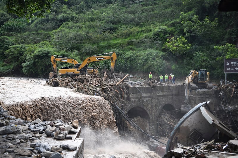 Excavators remove debris from a bridge in the aftermath of floods at Xinhua village (Wang Xi/Xinhua/AP)