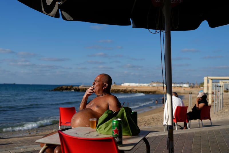 A man smokes at a beach cafe in Haifa, Israel (Ohad Zwigenberg/AP)