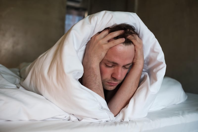 Stressed man lying in bed unable to sleep