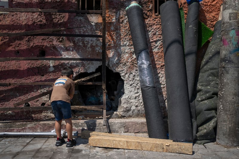 A child looks at at a hole in a wall at the scene of a bomb explosion in Tel Aviv, Israel (Ohad Zwigenberg/AP)