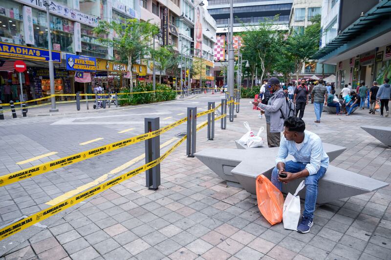 People sit next to a closed road after another deep sinkhole appeared in Kuala Lumpur (Vincent Thian/AP)