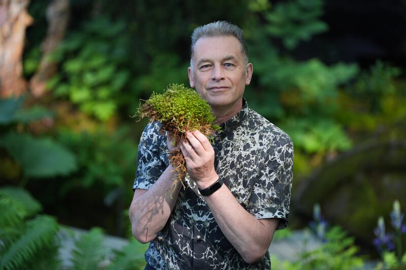 Chris Packham holds up moss on the National Autistic Society garden