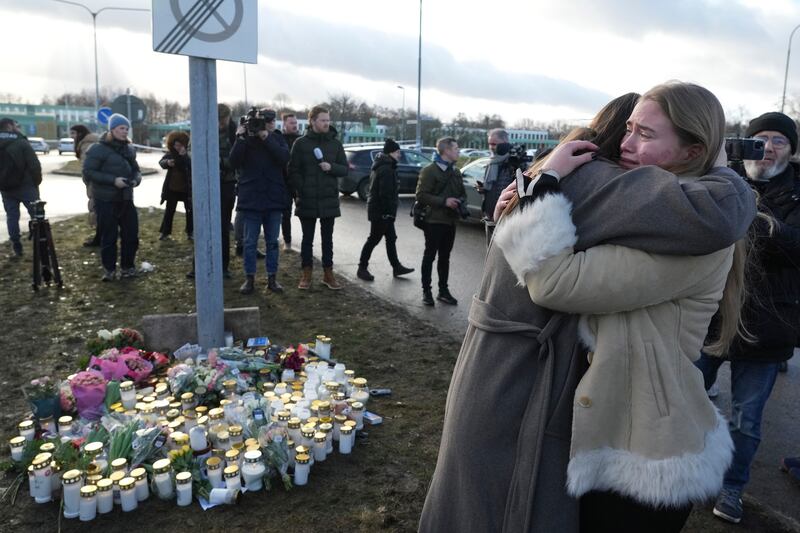 People gather at a makeshift memorial near the scene of a shooting on the outskirts of Orebro, Sweden (Sergei Grits/AP)