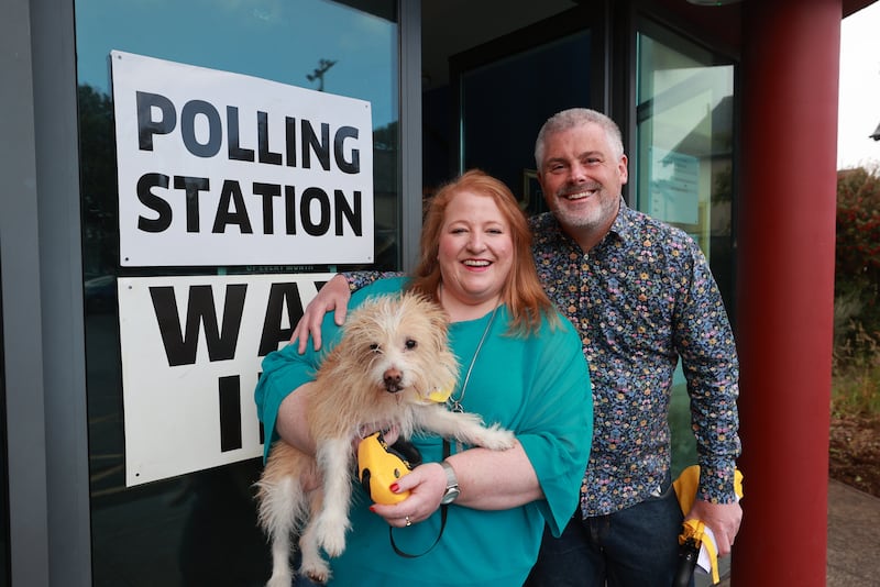 Alliance leader Naomi Long, her husband Michael and their dog Daisy outside the polling station at St Colmcille’s Church