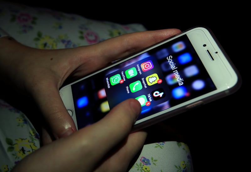 A young girl looks at social media apps on a phone