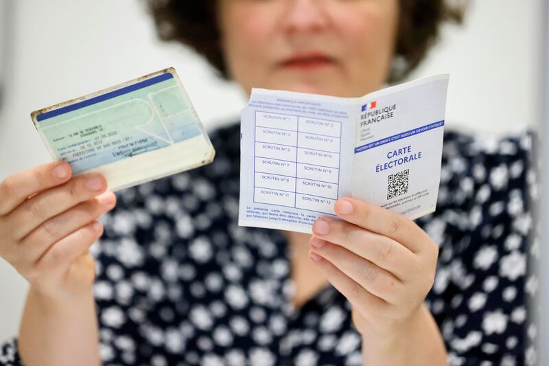 An election assistant checks a polling card and identity card at a polling station in Strasbourg, eastern France (Jean-Francois Badias/AP)