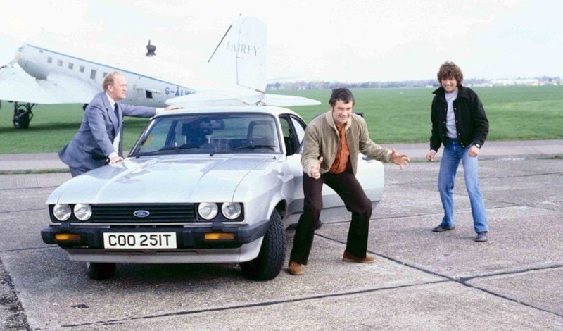 Cowley (Gordon Jackson), Bodie (Lewis Collins) and Doyle (Martin Shaw) pose on a runway beside one of the real stars of The Professionals, a Ford Capri 3.0 S