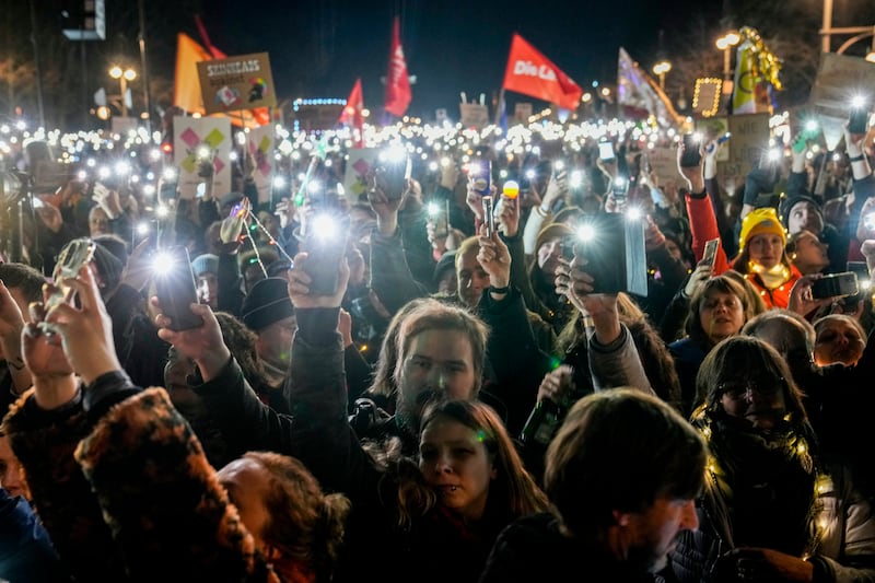 People hold up their cell phones as they protest against the far-right Alternative for Germany party (Ebrahim Noroozi/AP)