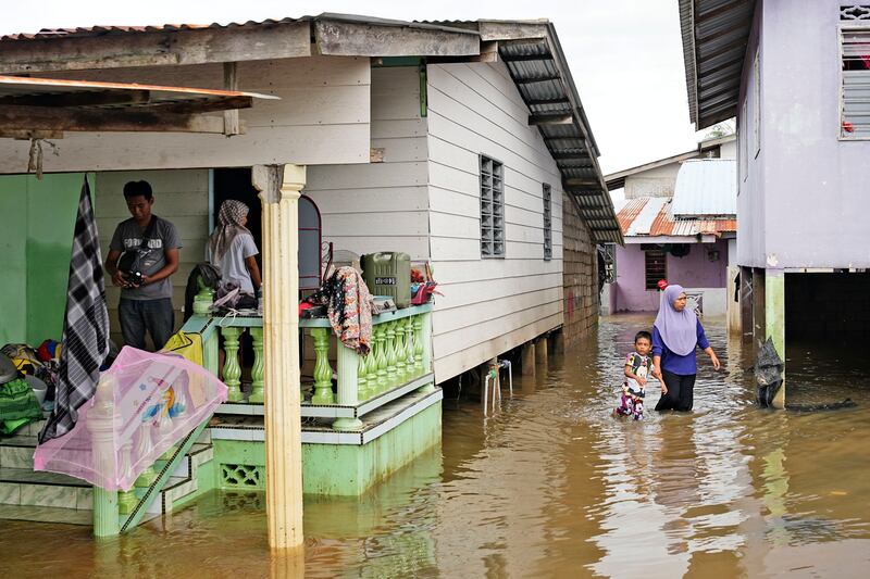 People wade through floodwater in a neighbourhood on the outskirts of Kota Bahru, Malaysia (Vincent Thian/AP)