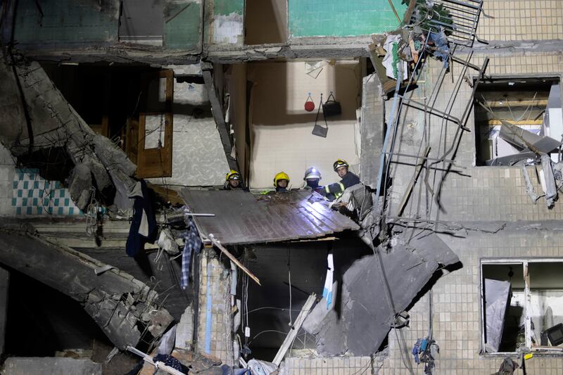 Rescue workers clear rubble from a building damaged by a Russian airstrike in Kharkiv (Yevhen Titov/AP)