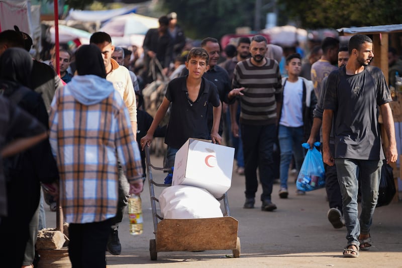 A Palestinian child carries humanitarian aid in Deir al-Balah (Abdel Kareem Hana/AP)