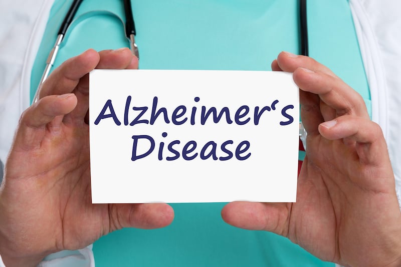 Close up picture of doctor holding a card with says Alzheimer’s Disease