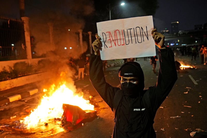 A protester holds a poster during a rally against controversial changes to election laws in Indonesia (Dita Alangkara/AP)