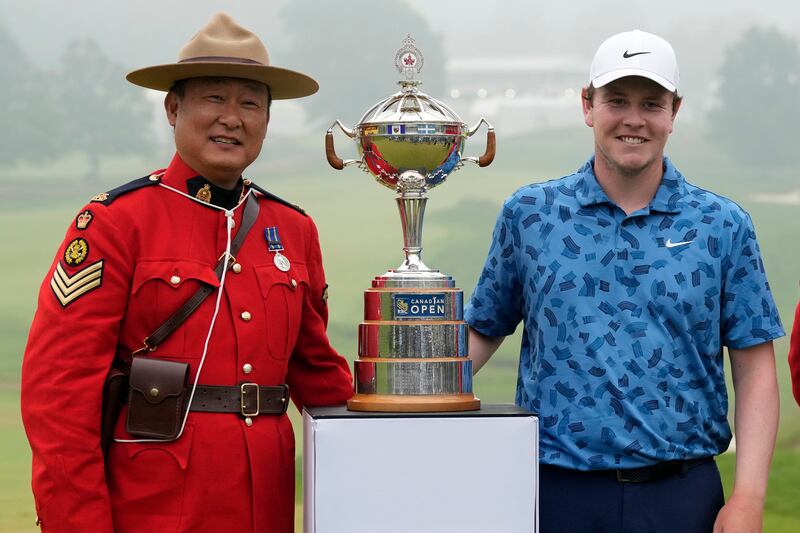 Scotland’s Robert MacIntyre (right) and an RCMP officer pose with the Canadian Open trophy (Frank Gunn/The Canadian Press via AP)