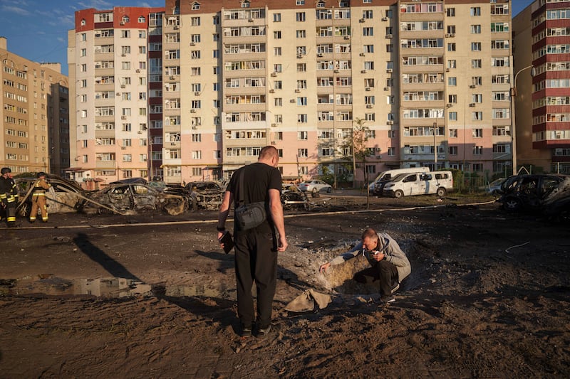 Young men look at shrapnel after a Russian air strike on a residential neighbourhood in Sumy, Ukraine (Evgeniy Maloletka/AP)