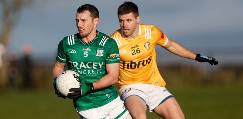 A Fermanagh GAA player runs away with the ball as he is pursued by an Antrim rival
