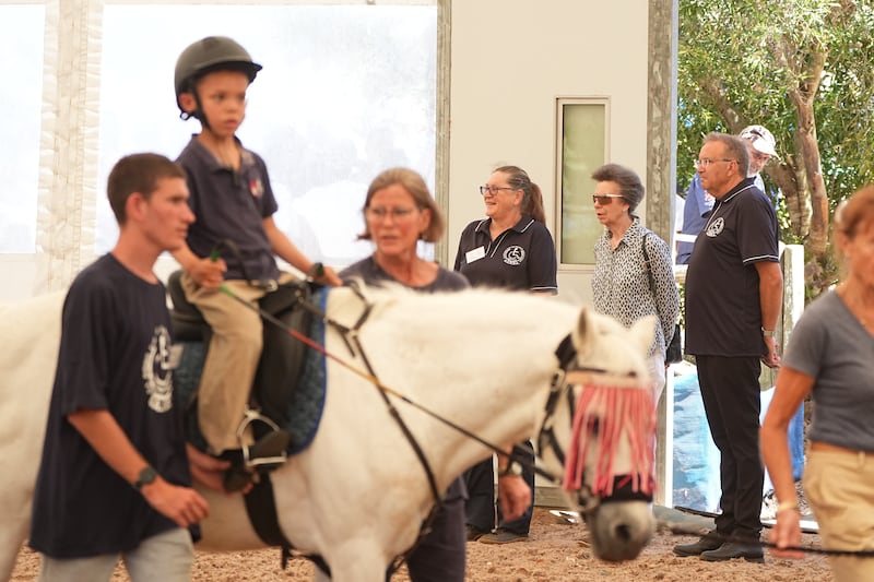 The Princess Royal views a riding lesson during a visit to the South African Riding School for Disabled Association while on her trip to South Africa