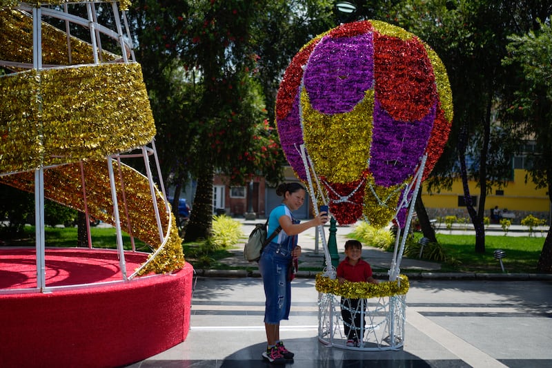 A woman takes a selfie with her daughter inside a Christmas decoration in Caracas (AP Photo/Ariana Cubillos)