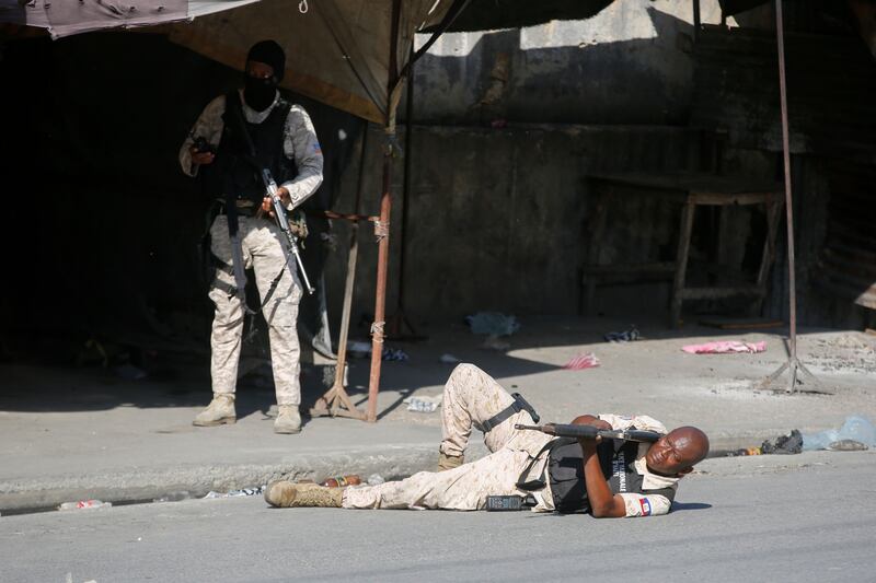 A police officer takes aim during clashes with gang members in Port-au-Prince, Haiti (AP)