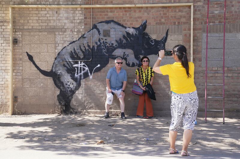 People have their picture taken by the now defaced artwork unveiled by Banksy, depicting a rhinoceros