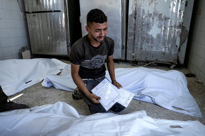 A Palestinian man mourns his four-day-old twin relatives, killed in the Israeli bombardment of the Gaza Strip, as he holds their birth certificates, at a hospital morgue in Deir al-Balah (Abdel Kareem Hana/AP)