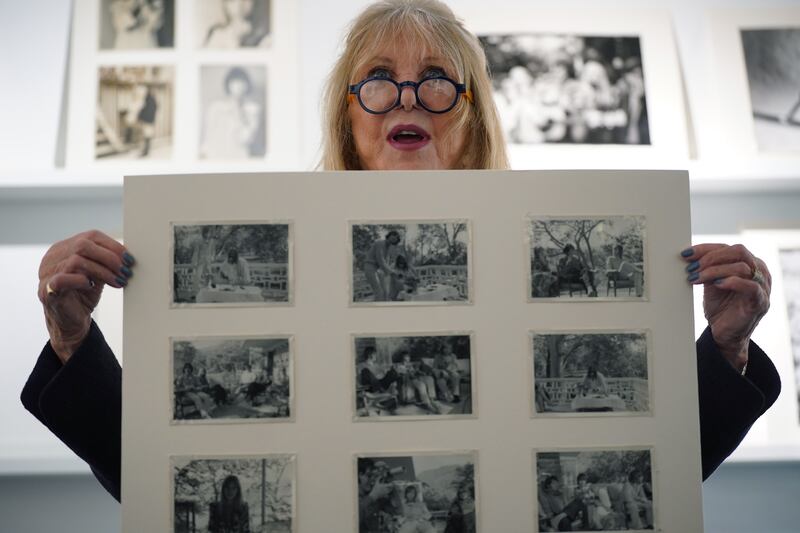Pattie Boyd holding a rare collection of eighteen original photographs taken during her time in Rishikesh, India, with all four Beatles and their wives and girlfriends