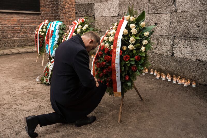 Polish president Andrzej Duda kneels in front of the Death Wall (Oded Balilty/AP)