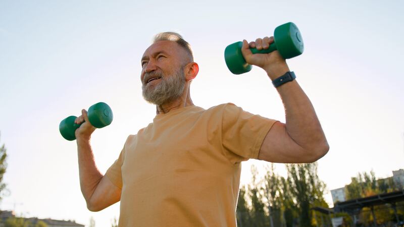 Old man lifting weights in a park