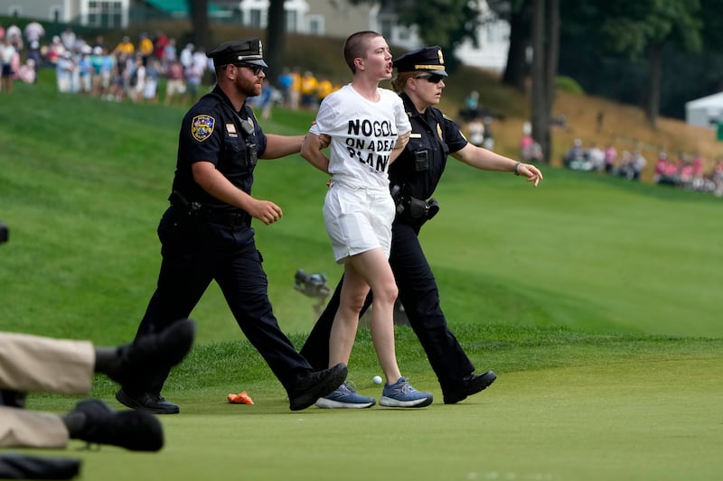 Protesters are led away after they ran onto the course on at the 18th hole during the final round of the Travelers Championship (Seth Wenig/AP)