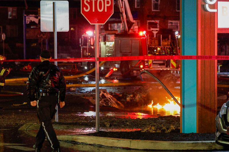 Fuel burns in the street after the plane crashed near Roosevelt Mall in Philadelphia (Steven M Falk/The Philadelphia Inquirer via AP)