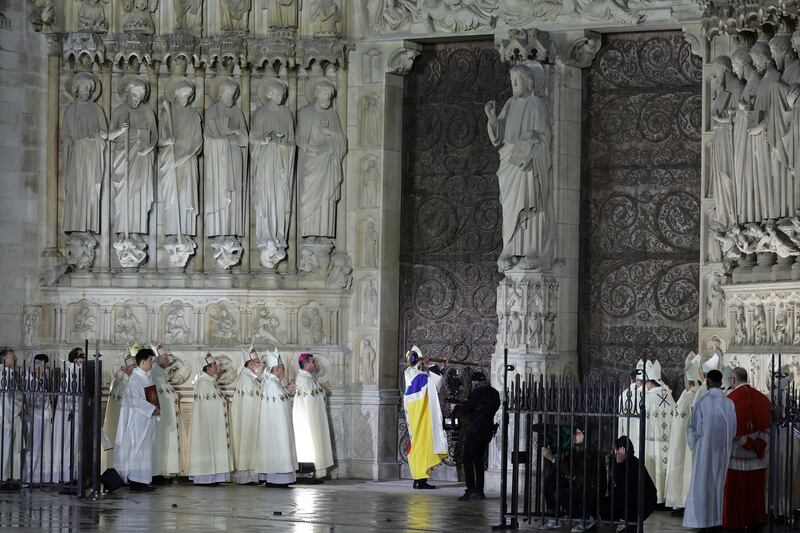 Paris’ archbishop Laurent Ulrich knocks on the doors of the cathedral to mark its reopening (Teresa Suarez, Pool via AP)