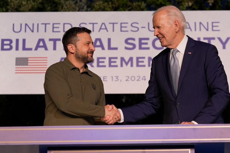 Joe Biden and Volodymyr Zelensky shake hands after signing a security agreement on the sidelines of the G7 on Thursday (Alex Brandon/AP)