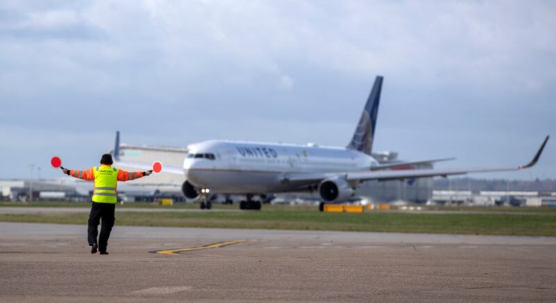 A airside operations member of staff guides in planes at Heathrow Airport