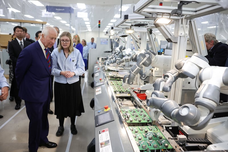 The King looks at robots on the production line