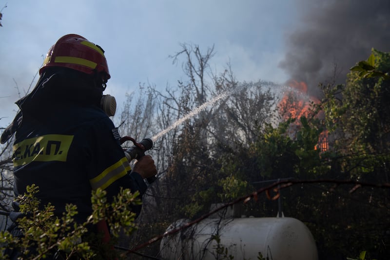 A firefighter sprays water with a hose in Varnava village during a wildfire (Michael Varaklas/AP)