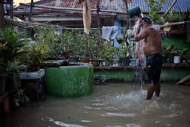 A resident takes a bath in a flooded village after Typhoon Yinxing, locally called Marce, ripped through the Philippines (AP/Noel Celis)