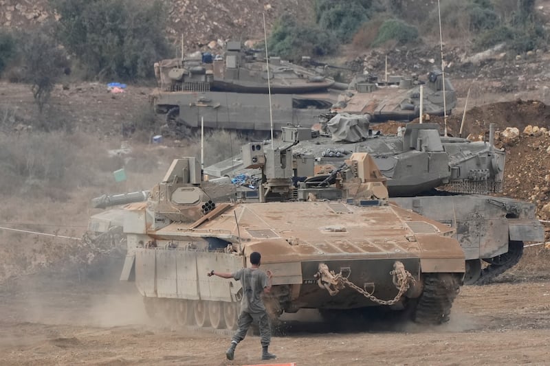 Israeli armoured personnel carriers and tanks manoeuvre in a staging area in northern Israel near the Israel-Lebanon border (Baz Ratner/AP)