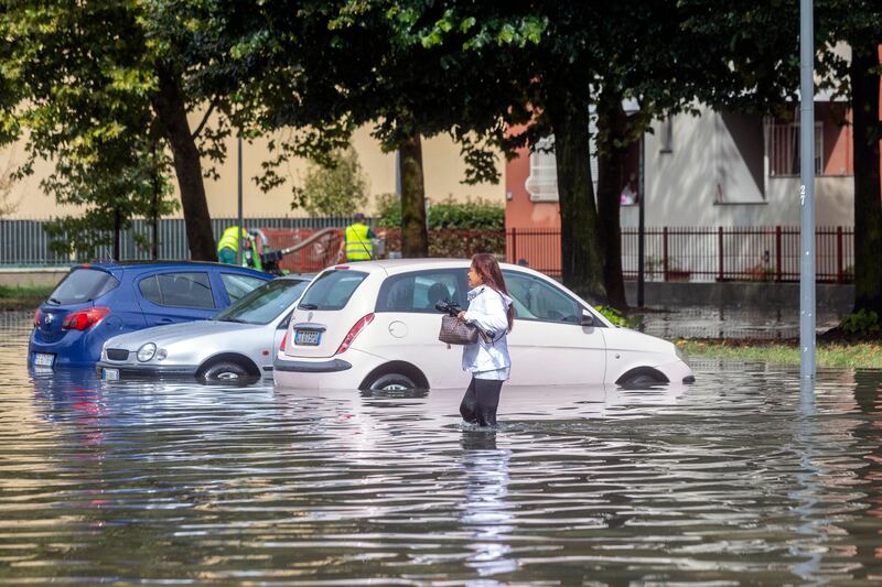 A woman wades through floodwater in Milan (Stefano Porta/LaPresse/AP)