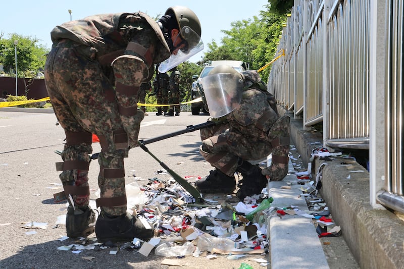 South Korean soldiers wearing protective gear examine the rubbish from a balloon sent by North Korea (Im Sun-suk/Yonhap/AP)