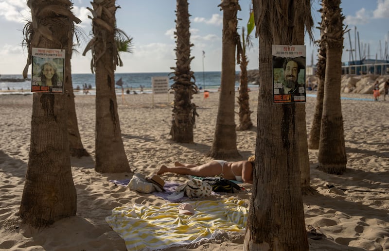 Signs calling for the release of hostages are plastered on trees in Tel Aviv’s beach in Israel (AP Photo/Ohad Zwigenberg)