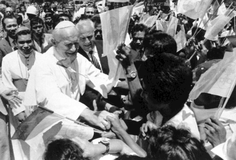 Pope John Paul II shaking hands with flag-waving local students upon his arrival in Dili, East Timor (Bullit Marquez/AP)