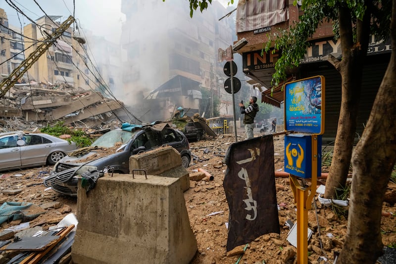 A man documents damaged buildings at the site of an Israeli airstrike in Beirut (Hassan Ammar/AP)