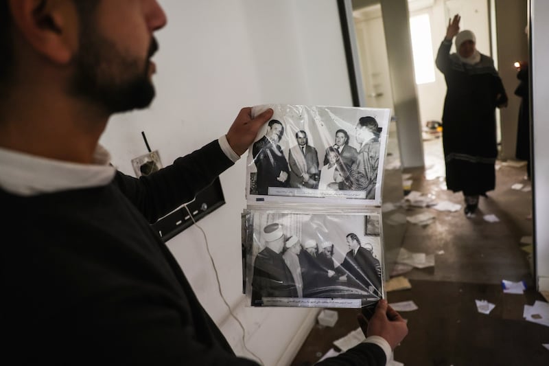 A man shows old pictures of the late Syrian president Hafez Assad as civilians ransack the private residence of overthrown President Bashar Assad in Damascus (Ghaith Alsayed/AP)