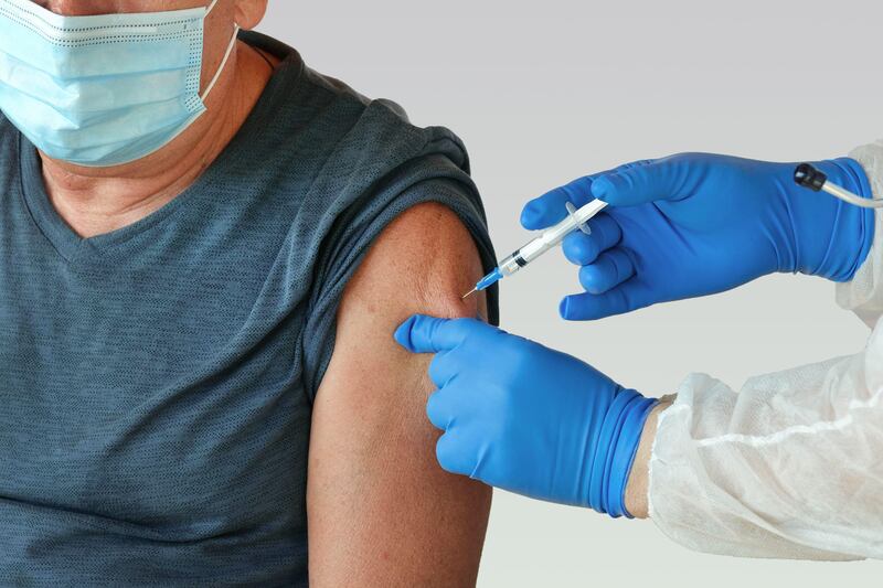 Doctor inserting mpox vaccine into senior man’s arm