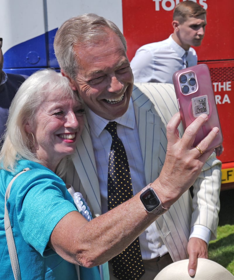 Reform UK leader Nigel Farage poses for a selfie with a supporter at an election rally in Maidstone, Kent