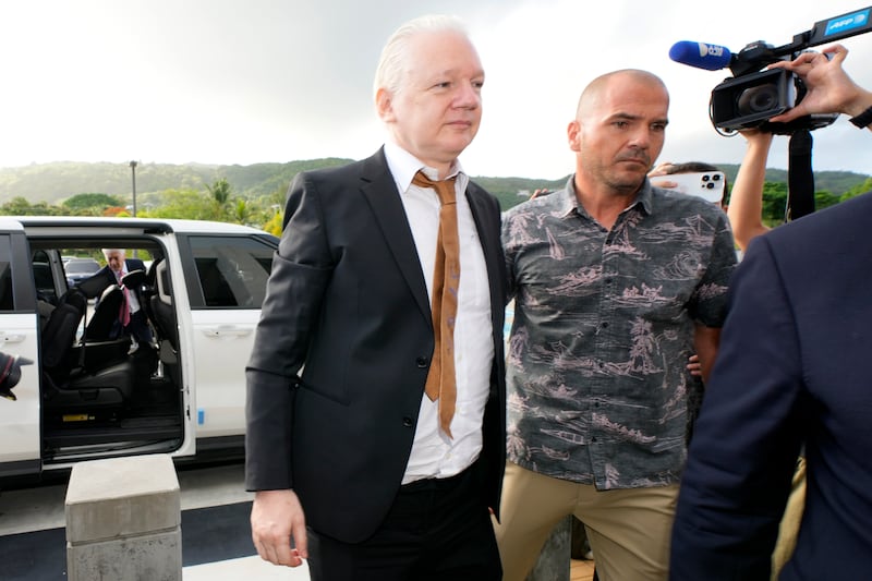 WikiLeaks founder Julian Assange, left, is escorted as he arrives at the United States courthouse, in Saipan, Mariana Islands (AP Photo/Eugene Hoshiko)